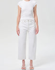Person wearing a white t-shirt and white jeans on a light gray background