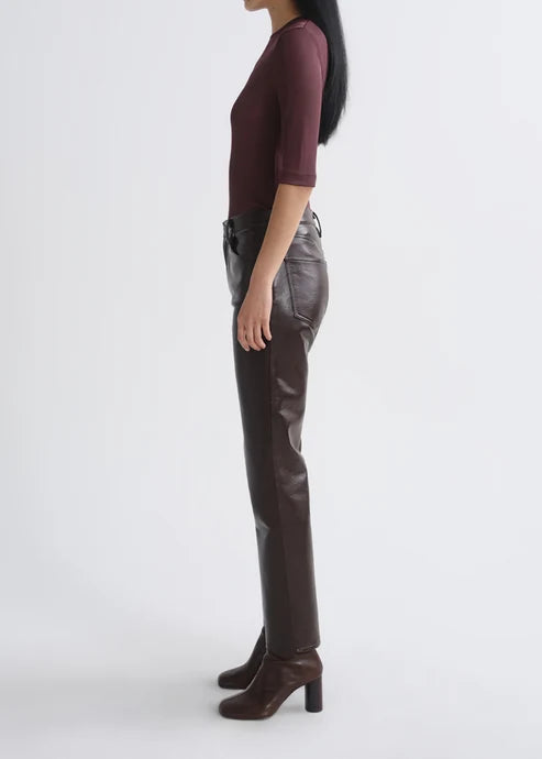 A model shown in profile wearing dark brown faux-leather trousers, a burgundy short-sleeve top, and matching brown heeled ankle boots against a plain light gray studio background.