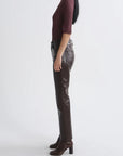 A model shown in profile wearing dark brown faux-leather trousers, a burgundy short-sleeve top, and matching brown heeled ankle boots against a plain light gray studio background.