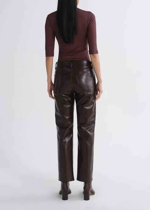 A model shown from the back wearing dark brown faux-leather straight-leg pants and a dark burgundy three-quarter sleeve top, set against a plain light gray studio background.