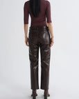 A model shown from the back wearing dark brown faux-leather straight-leg pants and a dark burgundy three-quarter sleeve top, set against a plain light gray studio background.
