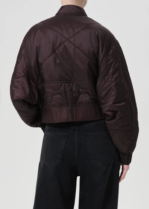 Person wearing a dark brown quilted jacket on a white background, back