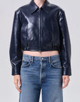 Person wearing a black leather jacket and blue jeans on a plain background