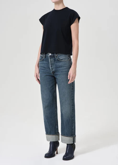 Person wearing a black top and blue jeans on a white background