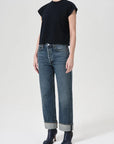 Person wearing a black top and blue jeans on a white background