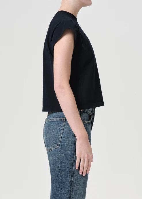 Person wearing a black top and blue jeans on a plain background