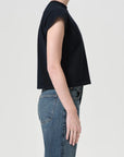 Person wearing a black top and blue jeans on a plain background
