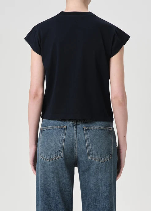 Person wearing a black sleeveless top and blue jeans on a plain background