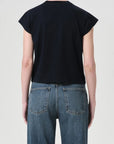 Person wearing a black sleeveless top and blue jeans on a plain background