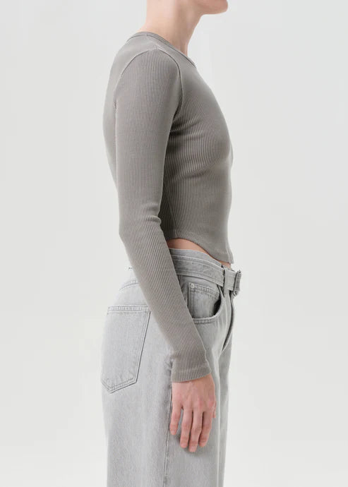 Person wearing a gray long-sleeve top and light gray jeans on a white background, side