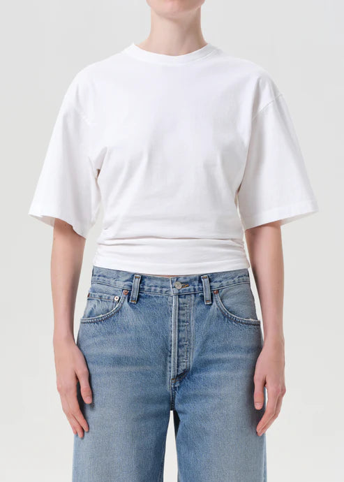 Person wearing a white t-shirt and blue jeans on a plain background