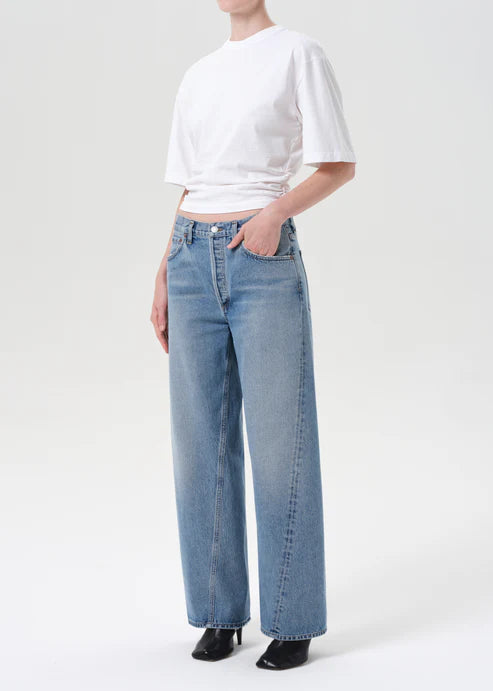 Person wearing a white crop top and light blue jeans on a white background