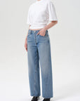 Person wearing a white crop top and light blue jeans on a white background