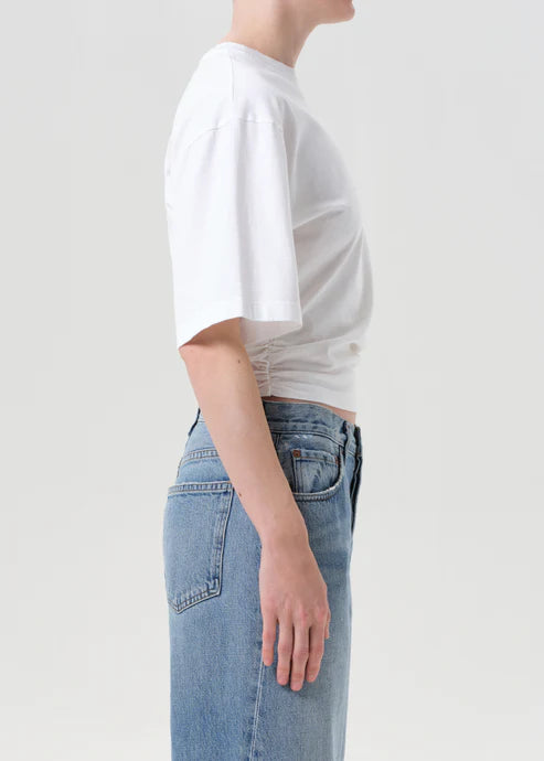 Person wearing a white t-shirt and blue jeans on a plain background