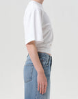 Person wearing a white t-shirt and blue jeans on a plain background