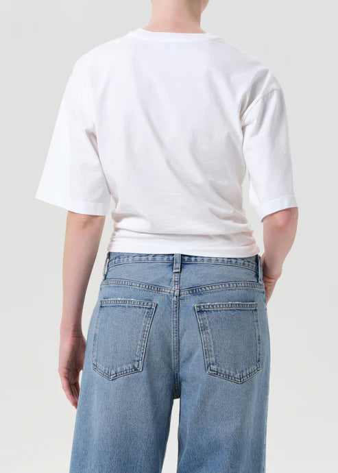 Person wearing a white t-shirt and light blue jeans against a plain background