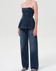 Person wearing a denim strapless top and wide-leg jeans on a white background