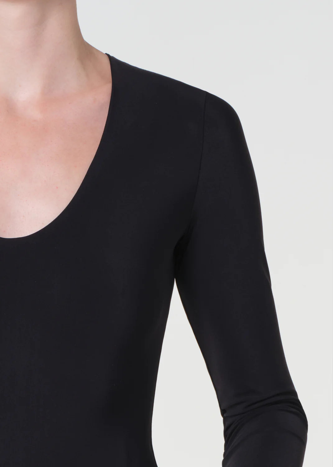 Black long-sleeve top worn by a person on a white background