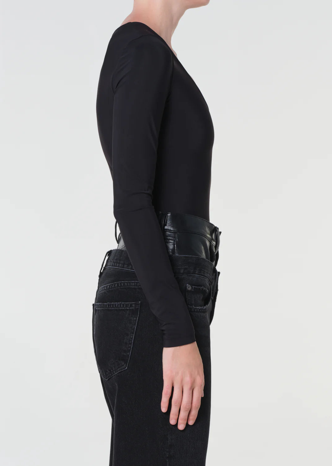 Person wearing a black long-sleeve top and black pants on a light gray background