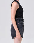 Person wearing a black sleeveless top and black denim shorts on a white background