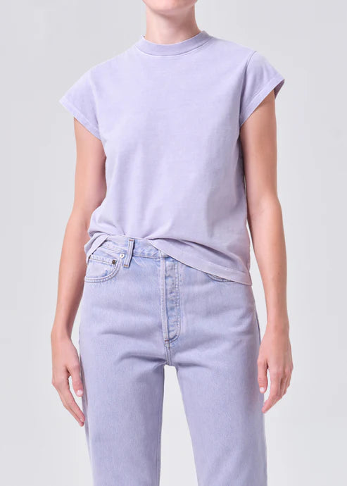 Person wearing a light purple t-shirt and jeans on a plain background