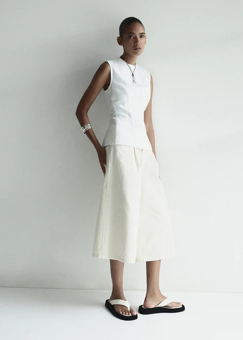 model wearing a white denim top and shorts with sandals on a white background
