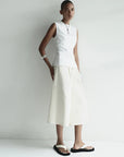 model wearing a white denim top and shorts with sandals on a white background