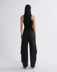 A model viewed from the back wearing a black sleeveless top and black wide-leg cargo pants against a light gray studio background.