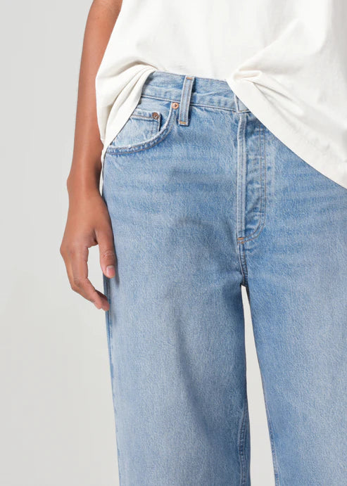 Light blue jeans worn by a person on a plain background detail view