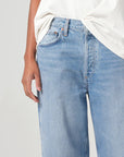 Light blue jeans worn by a person on a plain background detail view