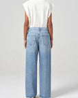 Person wearing light blue jeans and a white top on a plain background back view