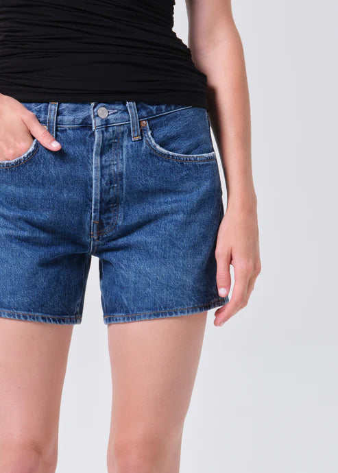 model wearing denim shorts with black shirt on a white background 