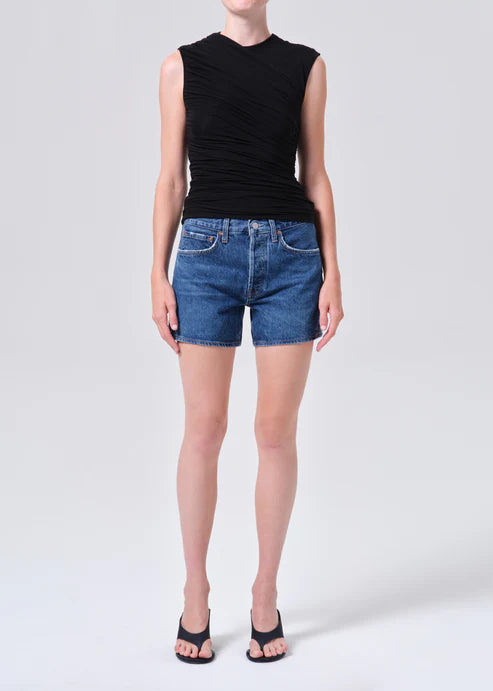model wearing denim shorts with black shirt and heels on a white background 