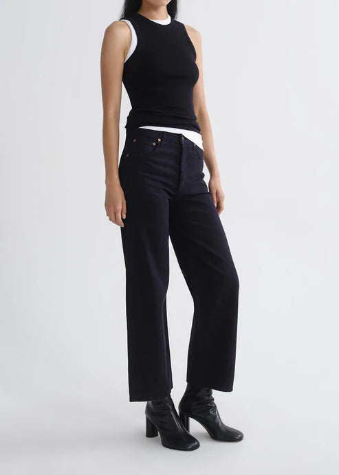 Person wearing a black sleeveless top and black pants on a white background