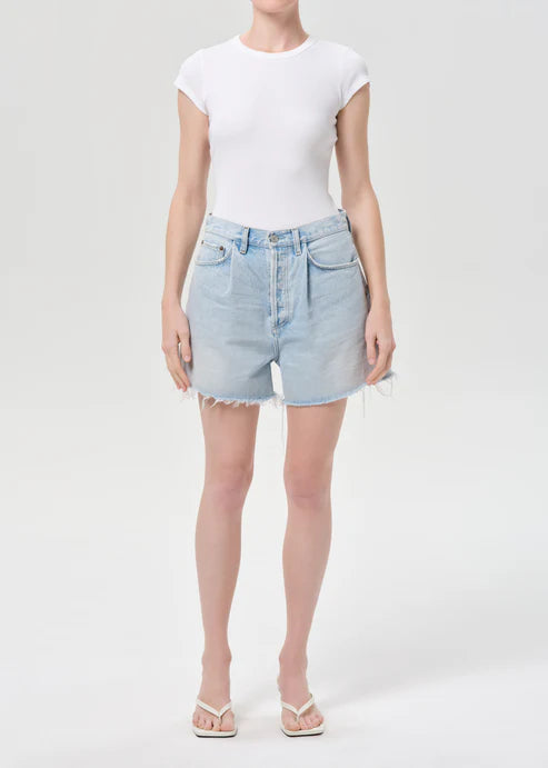 model wearing light wash denim shorts with a white top on a white background 