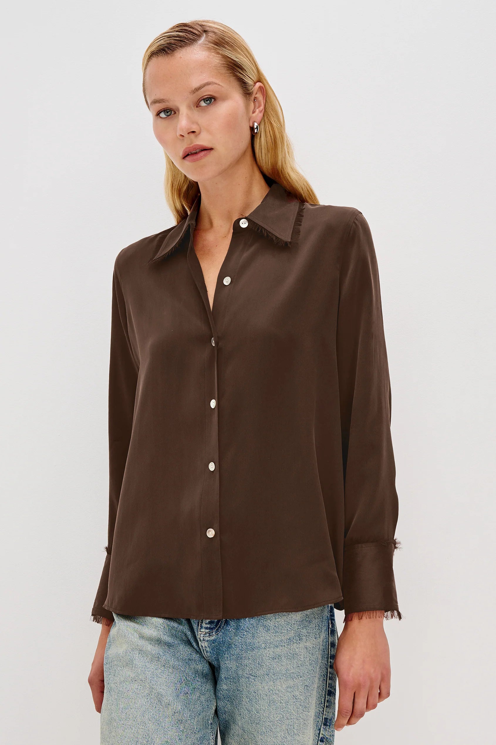 Woman wearing a brown button-up shirt and light blue jeans on a white background front