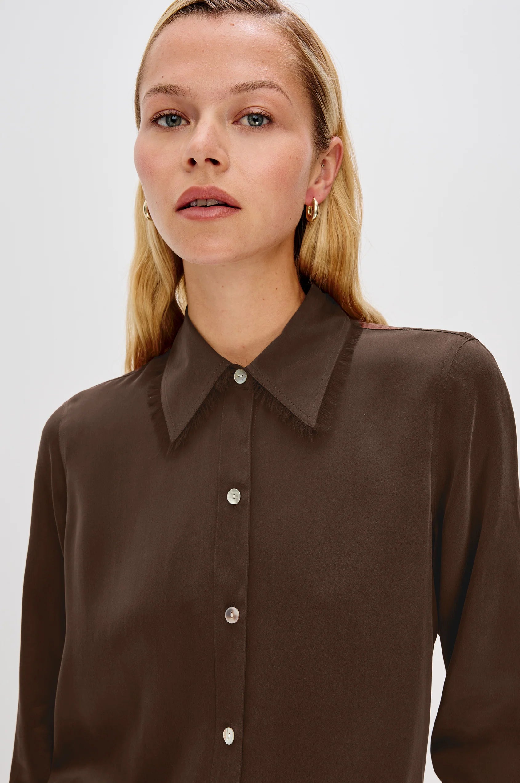 Woman wearing a brown blouse with a high collar on a white background