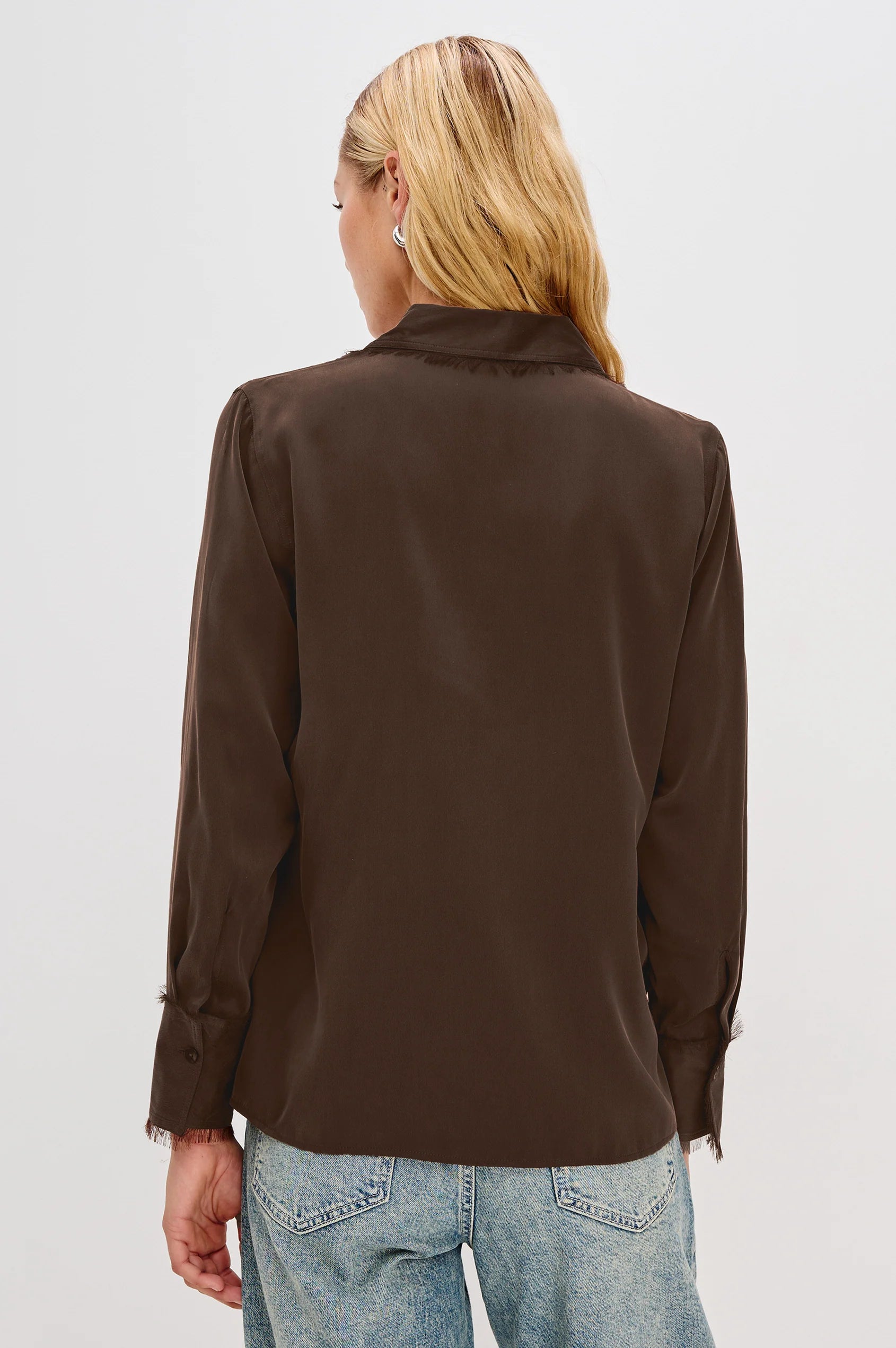 Person wearing a brown blouse and blue jeans on a white background back