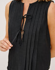 Black sleeveless top with a tie detail on a plain background