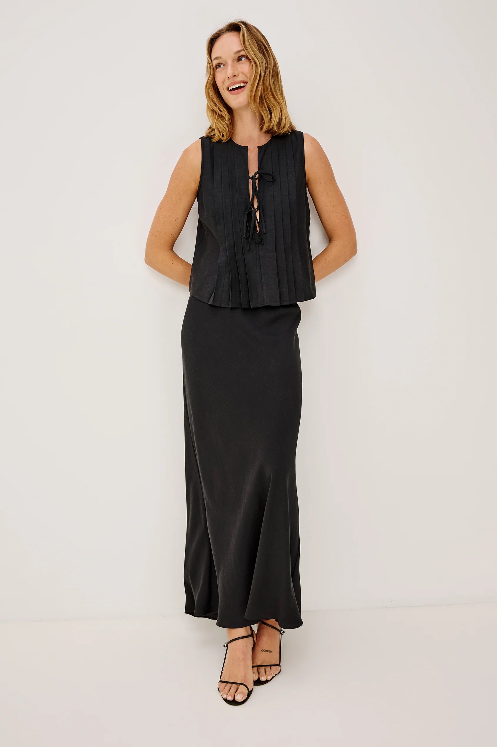 Woman wearing a black sleeveless top and black skirt against a white background