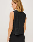 Woman wearing a black sleeveless top with a plain background
