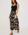Woman wearing a black top and patterned pants on a white background