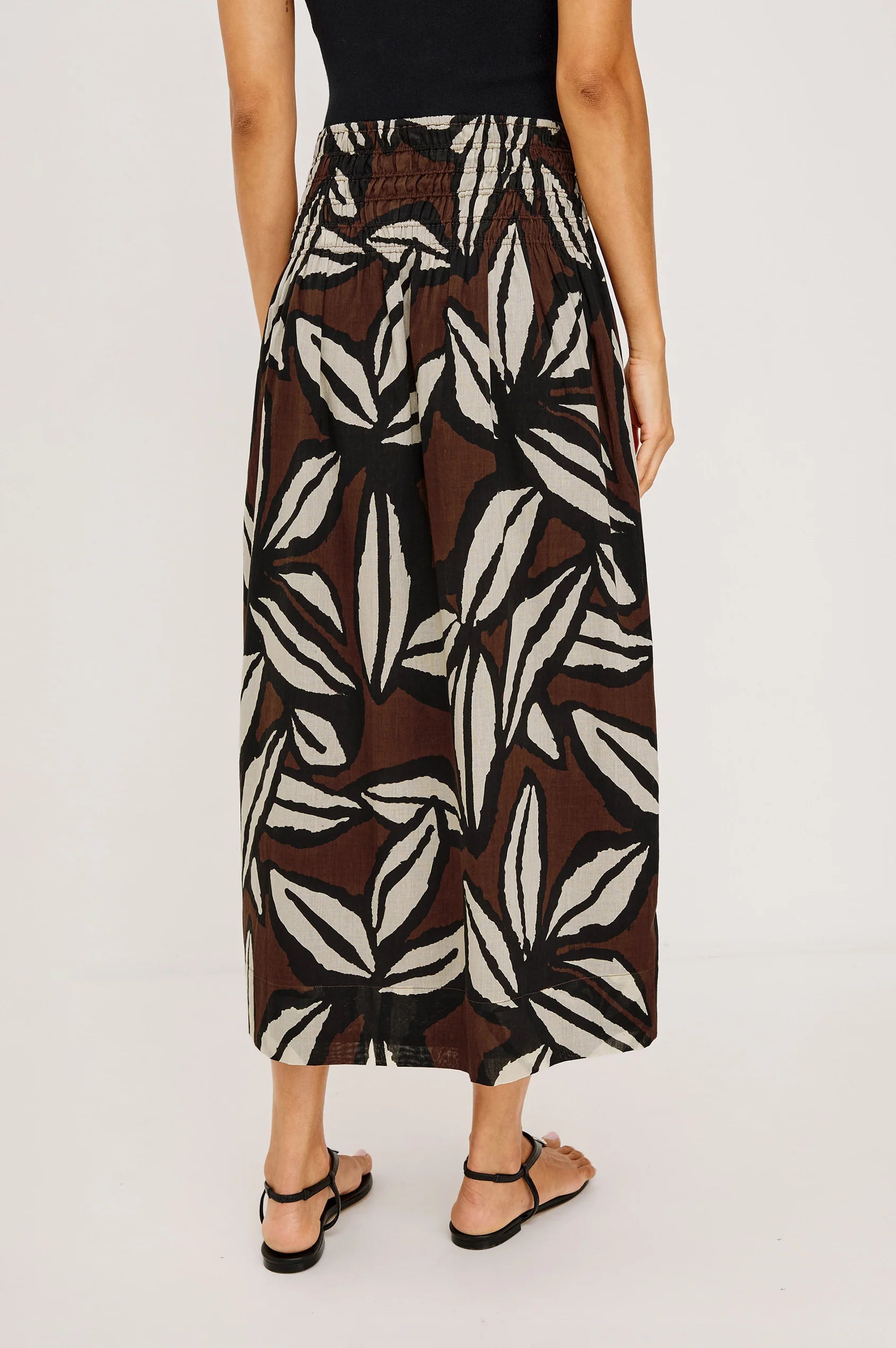 Person wearing a patterned skirt on a plain background
