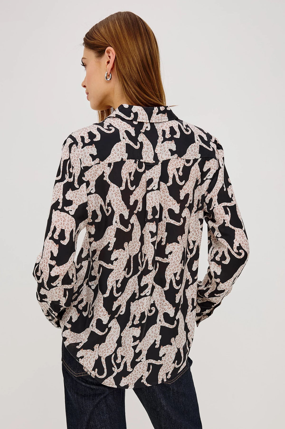 Woman wearing a black and white patterned blouse on a plain background