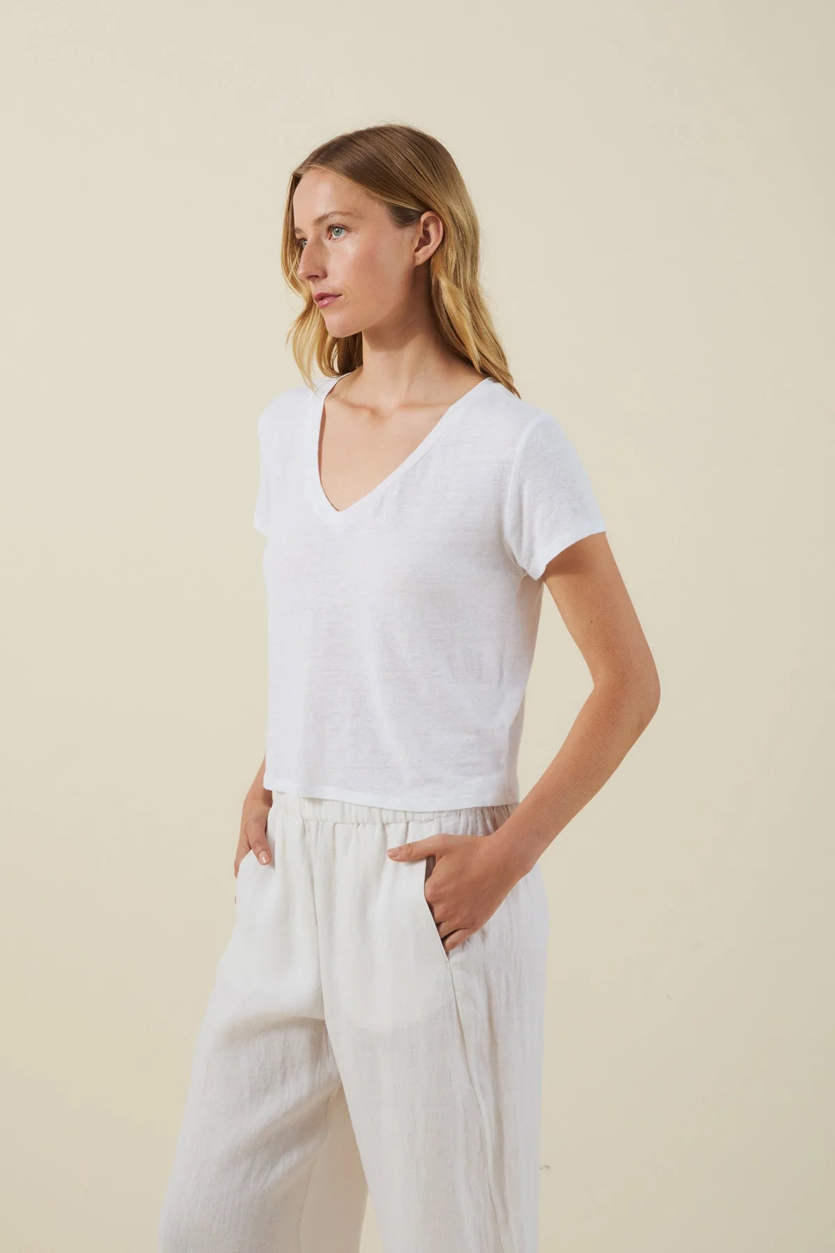 Woman wearing a white t-shirt and pants against a beige background