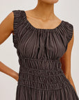 Woman wearing a brown pleated dress on a white background