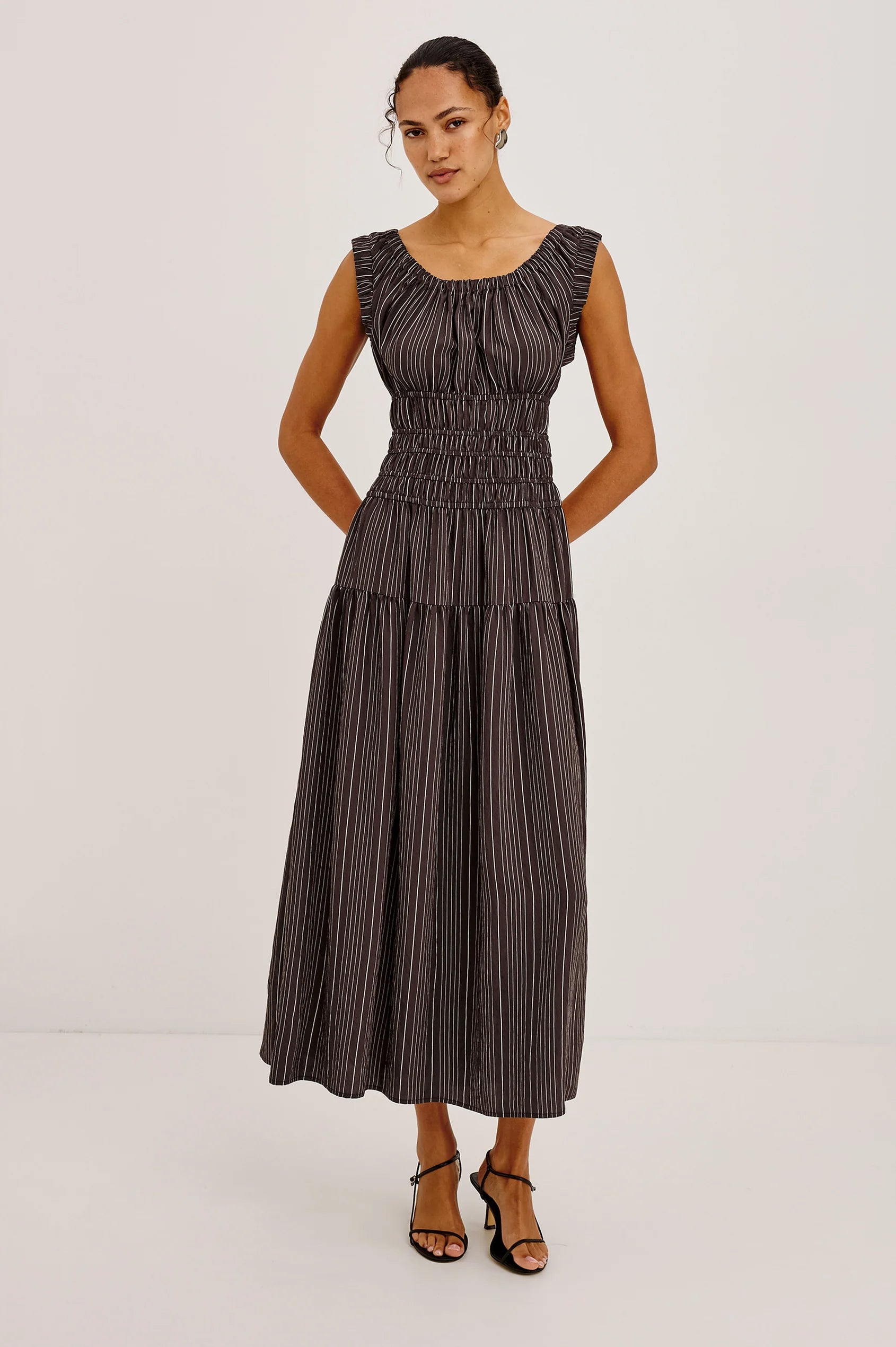 Woman wearing a dark striped dress on a light gray background