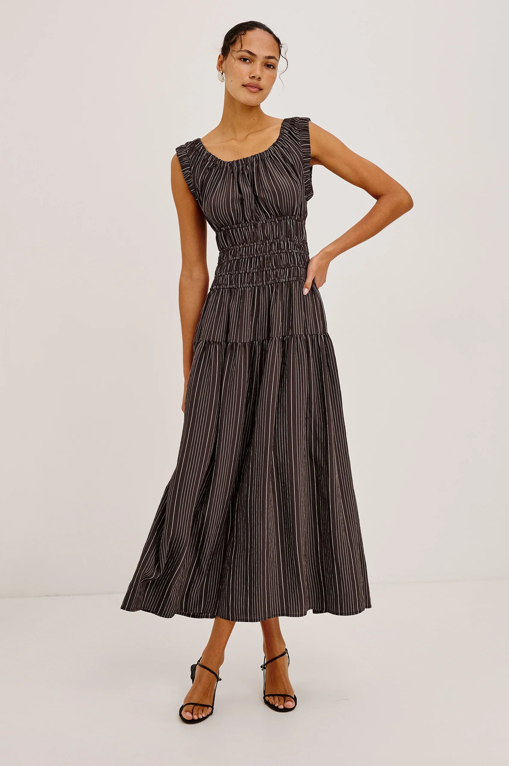 Woman wearing a dark striped dress on a light gray background