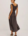 A woman modeling a sleeveless midi dress with vertical pinstripes in a dark gray and black colorway, shown from a three-quarter back angle against a plain white studio background.