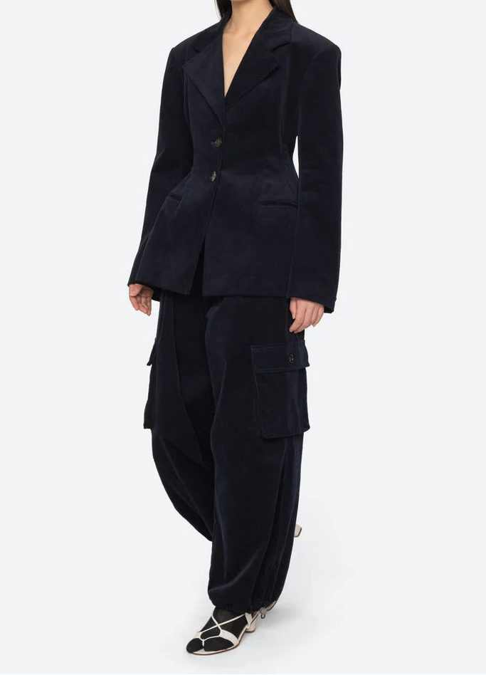 Person wearing a dark blue suit with cargo pants on a white background